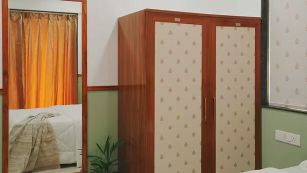Una camera da letto con un letto, un armadio, uno specchio e una pianta in vaso.