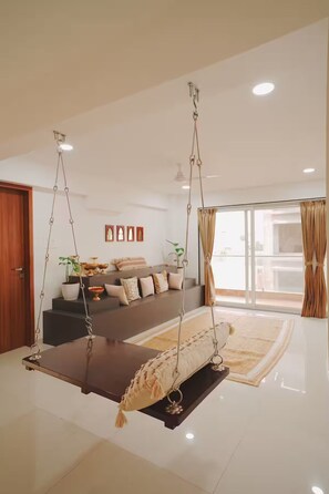 A modern living room with a suspended swing, a sofa set, and a large window.