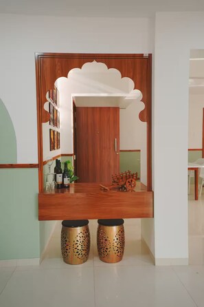 A reception area with a wooden counter, a white decorative panel, and two decorative stools.