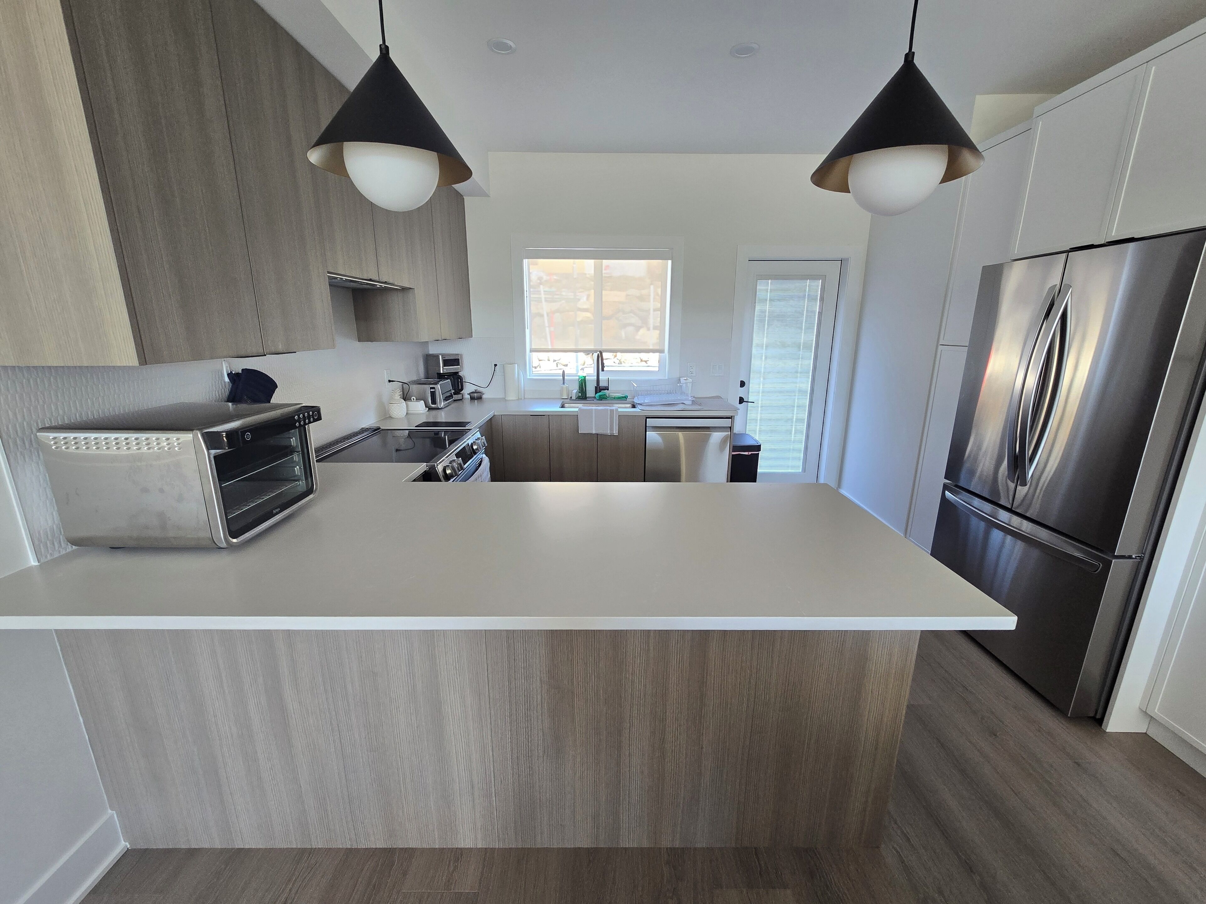 A modern kitchen with a central island, stainless steel appliances, and pendant lighting.