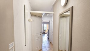 A hallway with white walls, a tiled floor, and doors leading to rooms. - 2-Bedroom Apartment in Les Rivages des Issambres (LES ISSAMBRES)