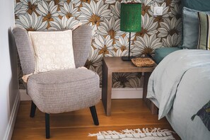 A bedroom with a patterned wallpaper, a chair, a bedside table with a lamp, and a bed. - Les Sentiers de Solutré Room (FUISSE)