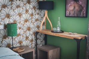 Een kamer met een groene wand, behang met een patroon, een houten tafel met een dienblad, een groene lamp en een lijstwerk met een kunstwerk.