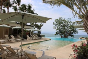 A poolside area with lounge chairs and umbrellas, a hot tub, and a view of the ocean. - Beachfront Penthouse at V Bucer as - Ocean Views (Bucerías)
