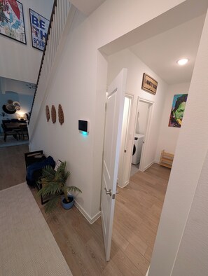 Een modern interieur met een trap, een bordje voor een wasserij en een eethoek met een lamp.