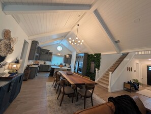 Un vaste loft doté d’un plafond haut, d’un coin repas, d’une cuisine et d’un escalier.