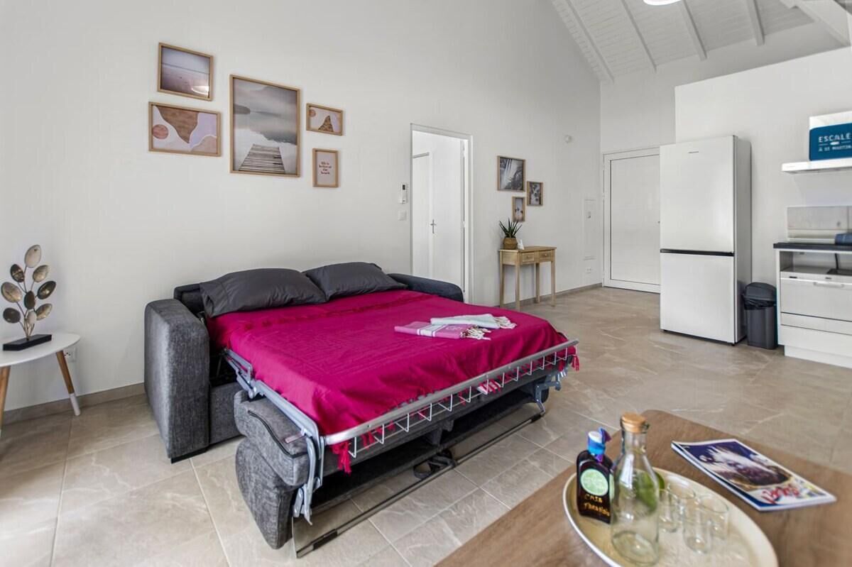 A bedroom with a bed, a small table with a tray of items, and a kitchenette area.