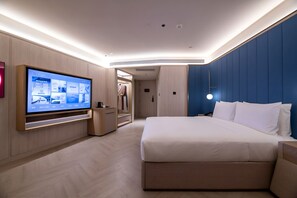 A modern hotel room with a large flat-screen TV, a bed with white linens, a walk-in closet, and a blue accent wall. - Crystal Hotel BJ Lize Biz Dis Center (Beijing)