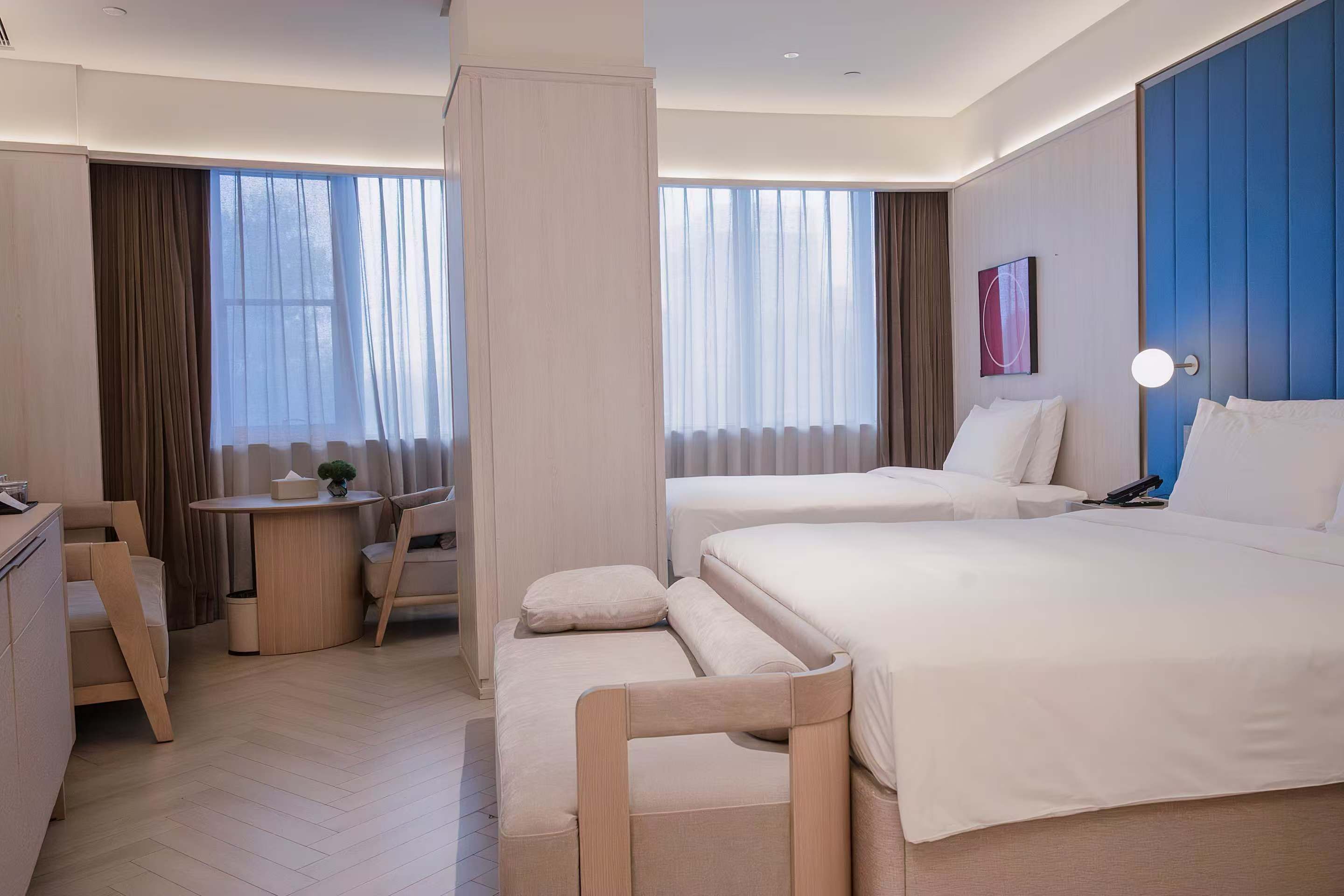 Een hotelkamer met twee bedden, een bureau en een stoel.