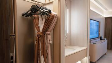 A hotel bathroom with a robe hanging on a rack, a sink, and a mirror.