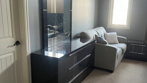 Ein Zimmer mit einem dunklen Holzschrank, einem hellen Sofa und einem großen Spiegel.