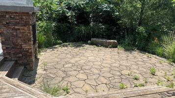 A stone patio with a brick wall and wooden deck.