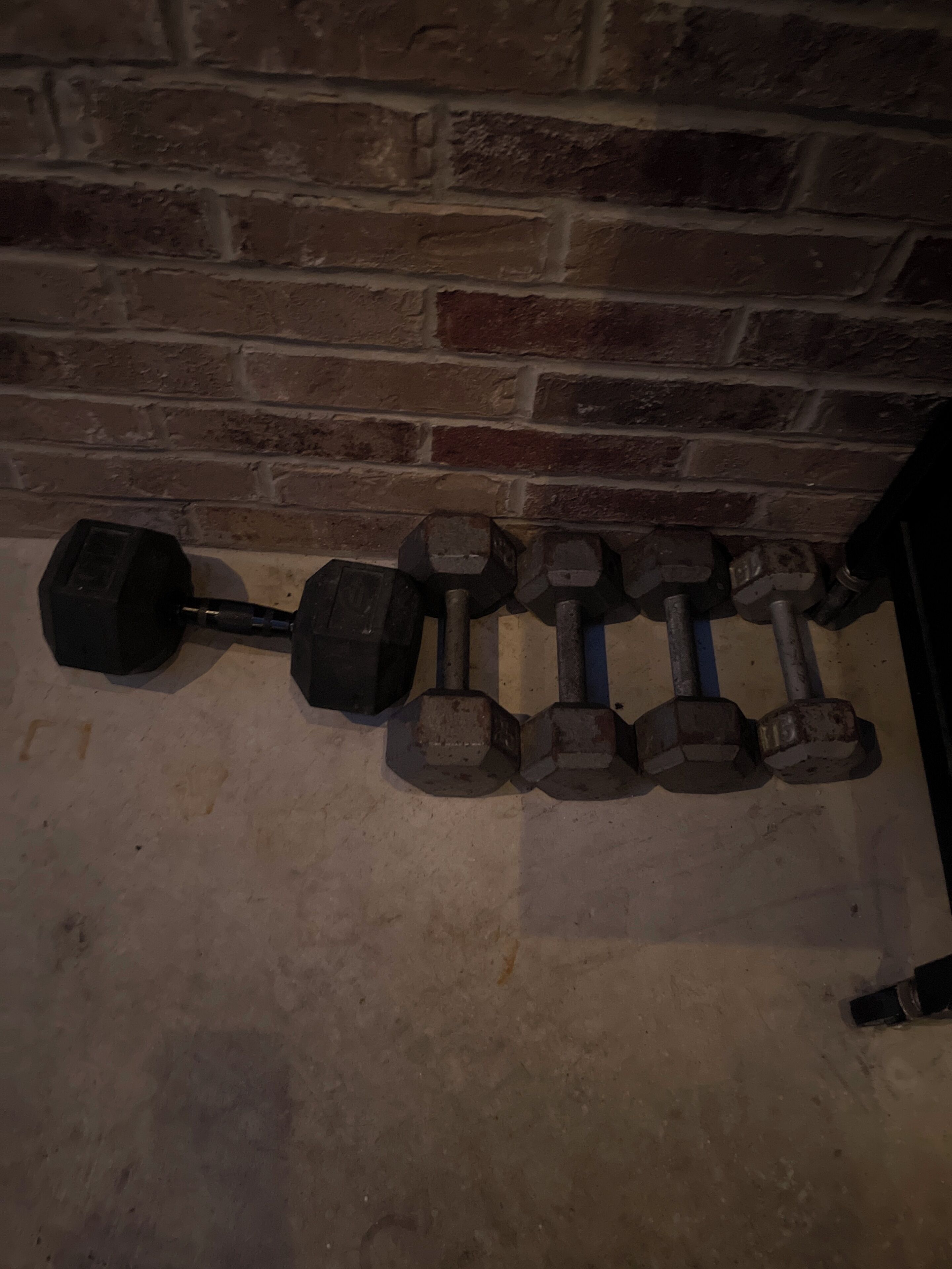 A row of dumbbells against a brick wall.
