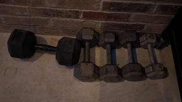 A row of dumbbells against a brick wall.