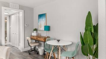 A modern room with a desk, chairs, a round table, and a large plant.