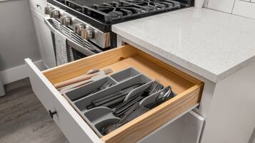 A kitchen with a stove, a drawer with utensils, and a countertop.