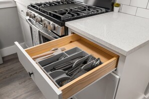 Una cocina con estufa, un cajón de utensilios y una encimera.