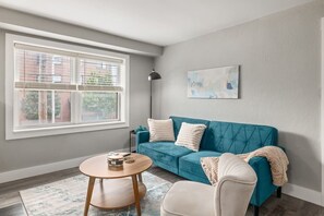 A room with a blue sofa, a round wooden table, and a single chair.
