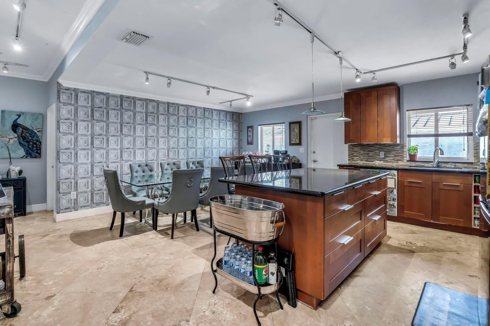 A spacious kitchen with a central island, a dining area with a glass table, and a patterned wall.