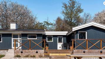 Een chalet met twee verdiepingen, een houten terras en een overdekt buitengebied.