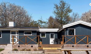 Eine zweistöckige Holzhütte mit einer Holzterrasse und einer überdachten Außeneinrichtung.