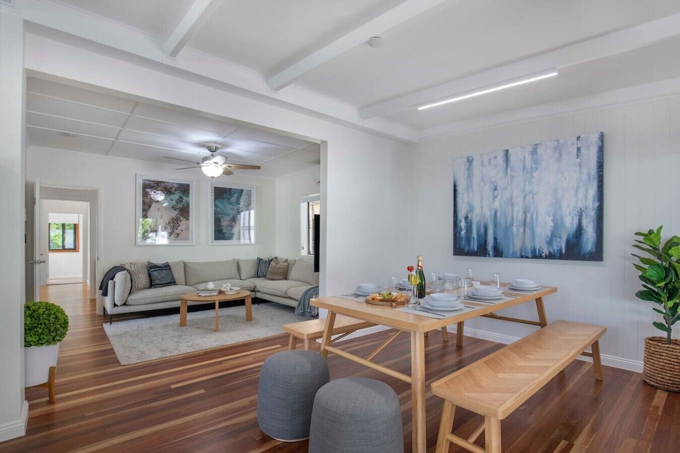 A modern living room with a sofa, a dining table set for four, and a large abstract painting on the wall.