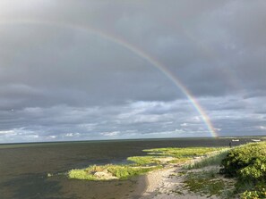 A coastal landscape with a rainbow, grassy areas, and a body of water. - Beautifully situated classic wooden summercottage (Hadsund)