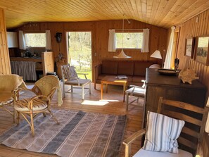 A cozy cabin interior with a dining area, seating, and a kitchen. - Beautifully situated classic wooden summercottage (Hadsund)