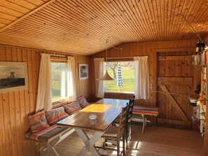 A wooden interior with a dining table, benches, and a bookshelf. - Beautifully situated classic wooden summercottage (Hadsund)