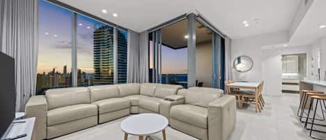 A modern living room with a sectional sofa, a round coffee table, and a dining area with a table and chairs.