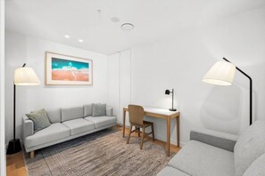 Ein modernes Wohnzimmer mit einem grauen Sofa, einem Holztisch und zwei Stehlampen.