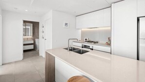 Ett modernt kök med en central köksö, inbyggda vitvaror och en minimalistisk design.
