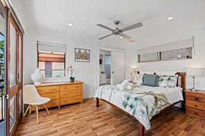 A bedroom with a bed, a dresser, a chair, a ceiling fan, and a window.