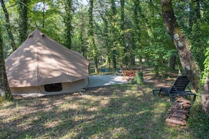 Una carpa montada en una zona boscosa con una mesa de picnic y sillas cerca.