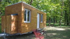 Eine kleine Holzhütte mit einer Schiebetür, einem Fenster und einem Tisch mit Stuhl.