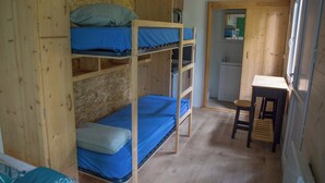 Ein kleines Zimmer mit Etagenbetten, einer kompakten Küchenzeile und einem Fenster.