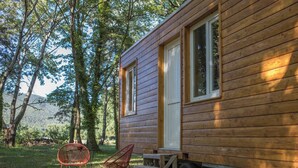 Eine Holzhütte mit einer Schiebetür, einer kleinen Veranda und einem Esstisch mit Stühlen.
