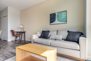 A modern living room with a grey sofa, a wooden coffee table, and a desk with a chair. - Blueground | Edgewater, gym, nr Lake Michigan (Chicago)