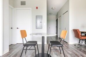 A room with a round table and two chairs, a door, a wall-mounted light, and a ceiling vent. - Blueground | Edgewater, gym, nr Lake Michigan (Chicago)
