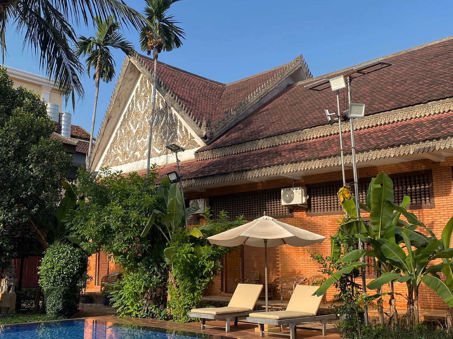 A traditional building with a tiled roof, a swimming pool, and lounge chairs.