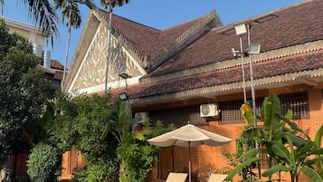 A traditional building with a tiled roof, a swimming pool, and lounge chairs.