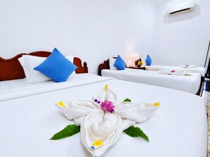 Une chambre d’hôtel avec deux lits, chacun agrémenté de draps blancs et d’oreillers bleus, et une serviette décorative posée sur le lit.