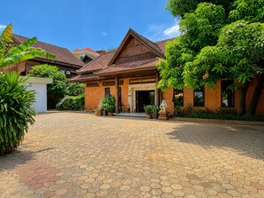 Un bâtiment traditionnel en bois, doté d’une entrée carrelée et d’une cour dallée.