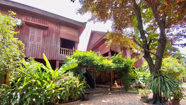 A courtyard with a wooden building, potted plants, and a stone-paved walkway. - ASANA (Siem Reap)