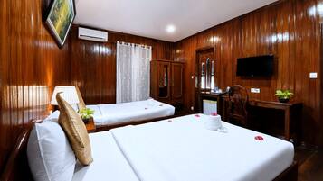 A hotel room with two beds, a desk, a television, and wooden paneling.