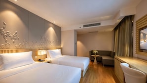 Een hotelkamer met twee bedden, een bank, een tafeltje en een televisie.