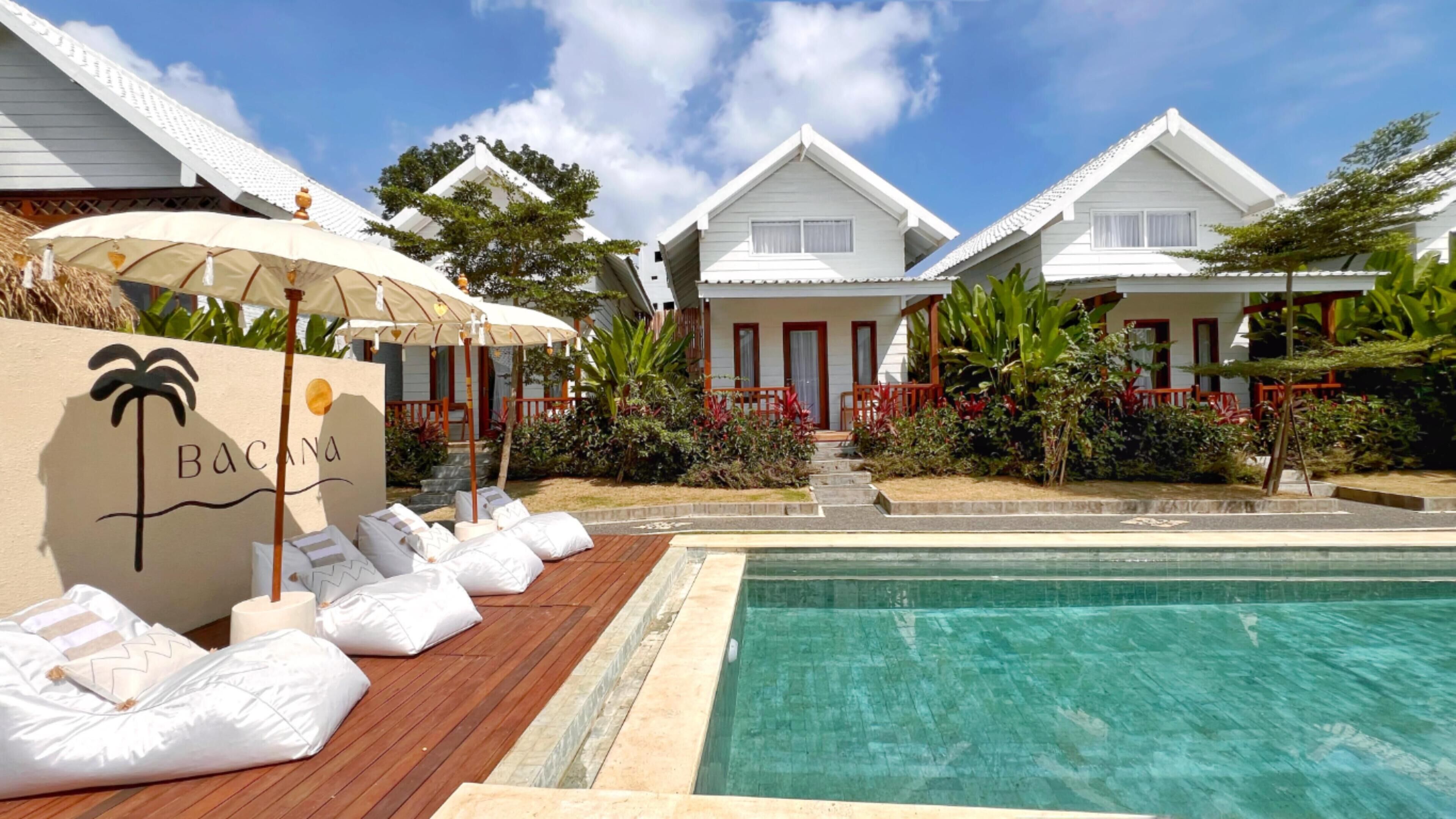 A resort with a pool, white buildings, and a sign reading 'BACONA'.
