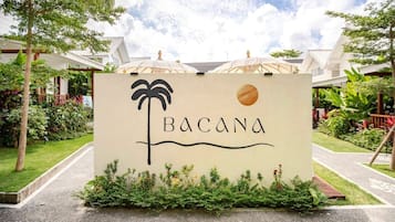 A sign with palm tree and sun icon, labeled 'BACANA' in a resort setting.