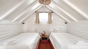 A bedroom with two beds, a window with curtains, and a wooden ceiling.