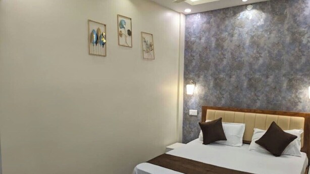 Une chambre d’hôtel avec un lit, une tête de lit et des œuvres d’art accrochées au mur.